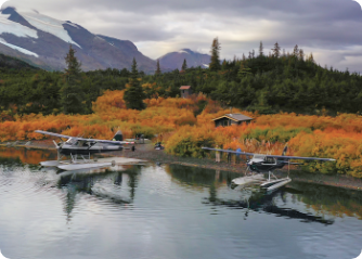 Two seaplanes docked in lake by mountains