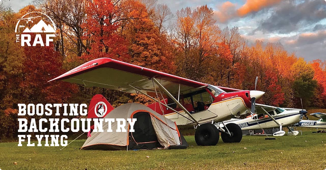 Airplane next to tent in field clearing